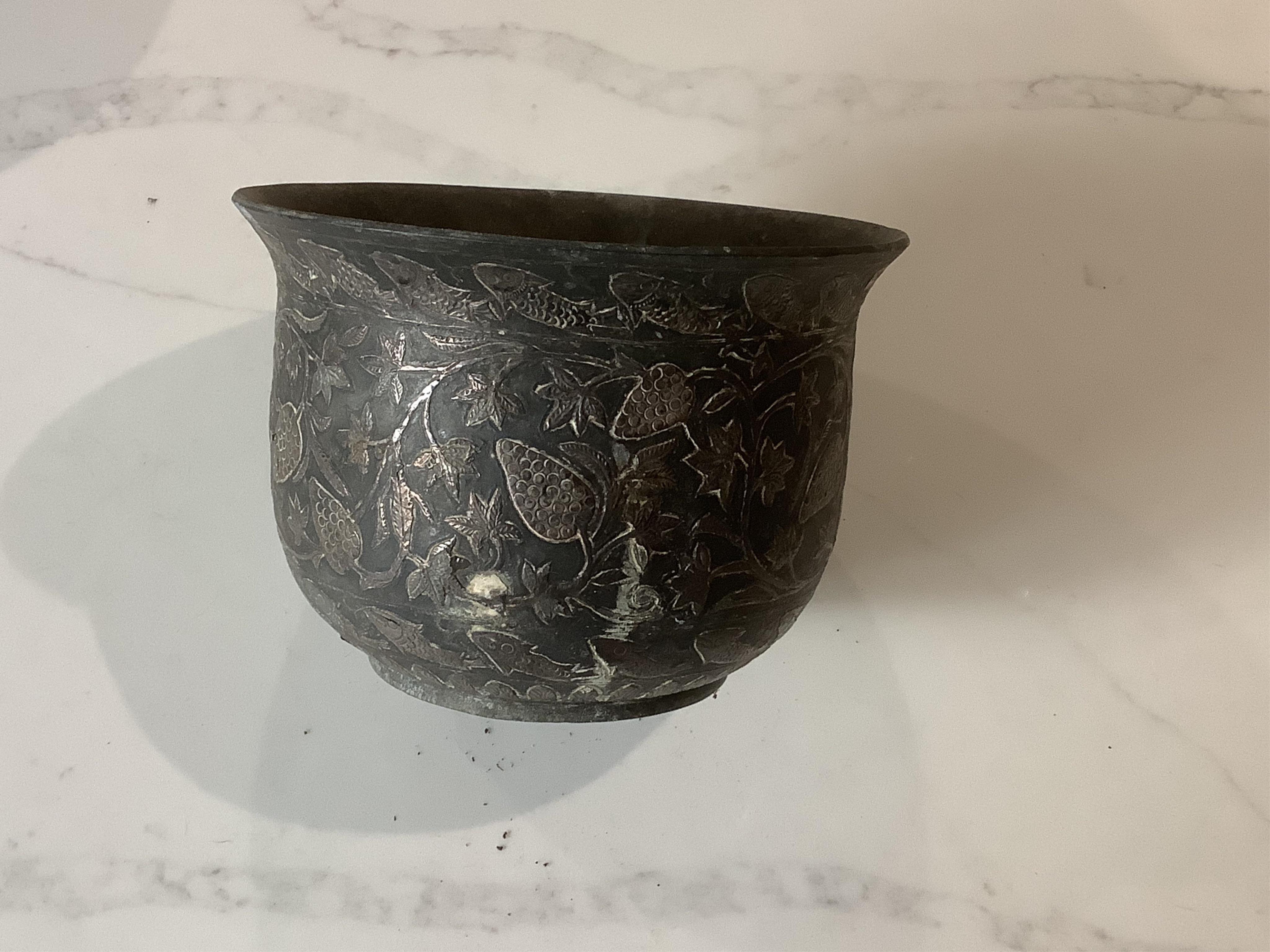 An Indian bidriware jardiniere decorated with fruiting plants and fish, 12.5cm and an embossed brass jardiniere decorated with monkey gods, 17.5cm.